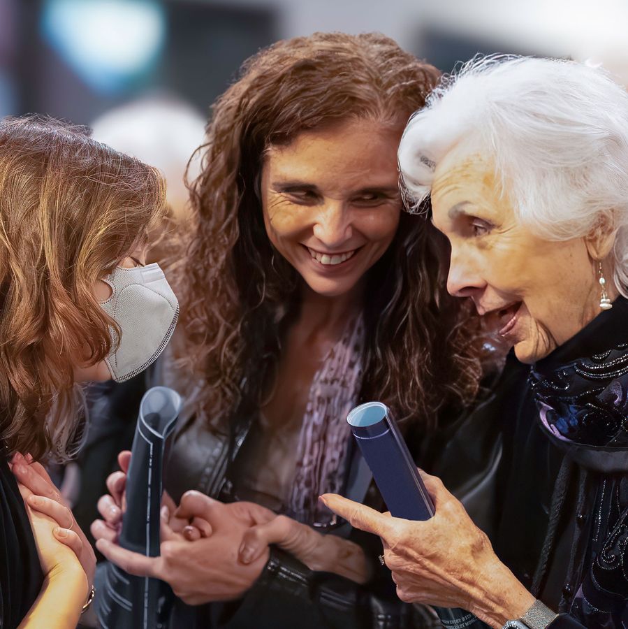Three women smiling and having an intimate conversation in the lobby after a show.
